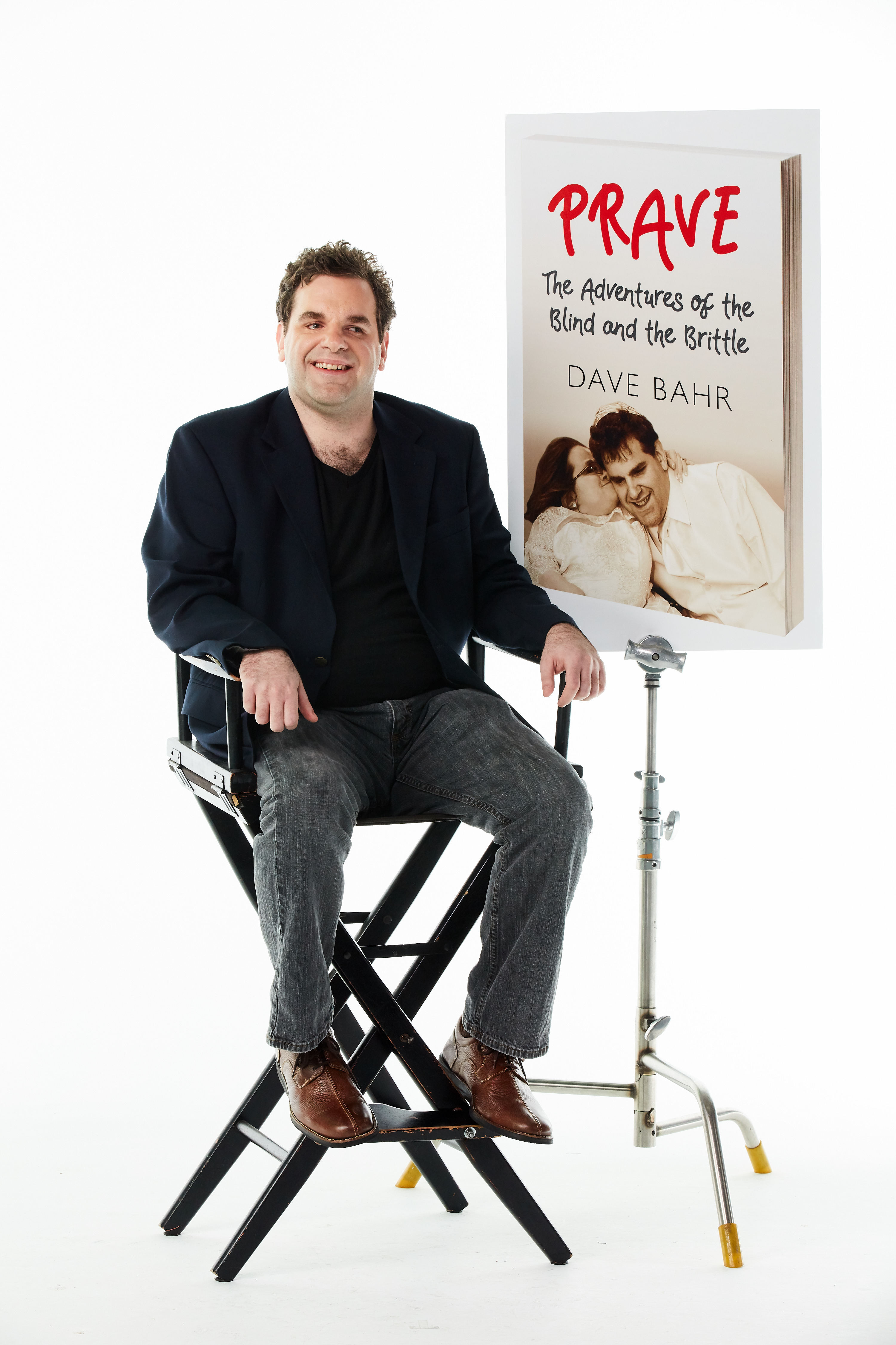 Dave in director's chair with a poster of the book cover seen over his shoulder.